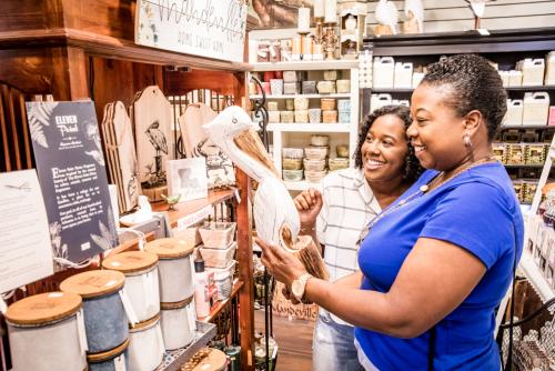 Two women standing in the aisle of a gift store in Mandeville, Louisiana looking at a carved wooden pelican