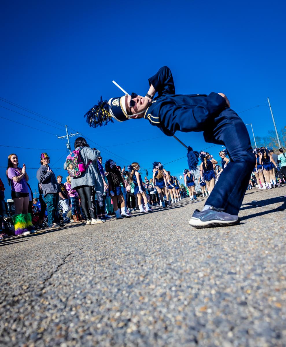 A high school band drum major in a backbend before the Krewe of Dionysus Mardi Gras parade in Slidell.