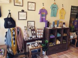 Shirts hang on the wall above jewelry and accessories at Black Flower Apparel in Covington, LA