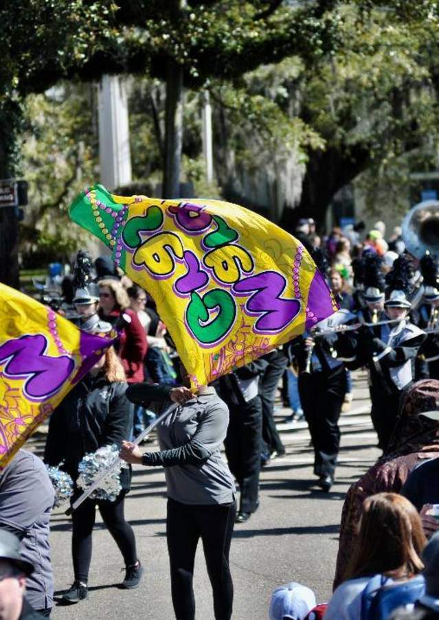 A flag corp marching in the 2019 Carnival in Covington Parade